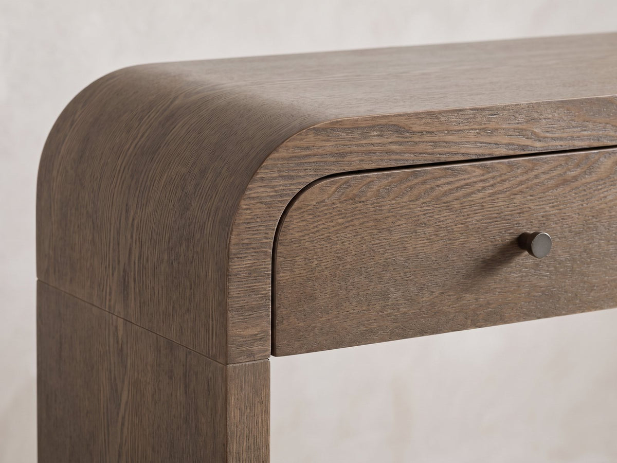 Close-up of the Adelfia Ash Veneer Waterfall Console Table: the curved end of the top running down into the end panel, beside the outer drawer