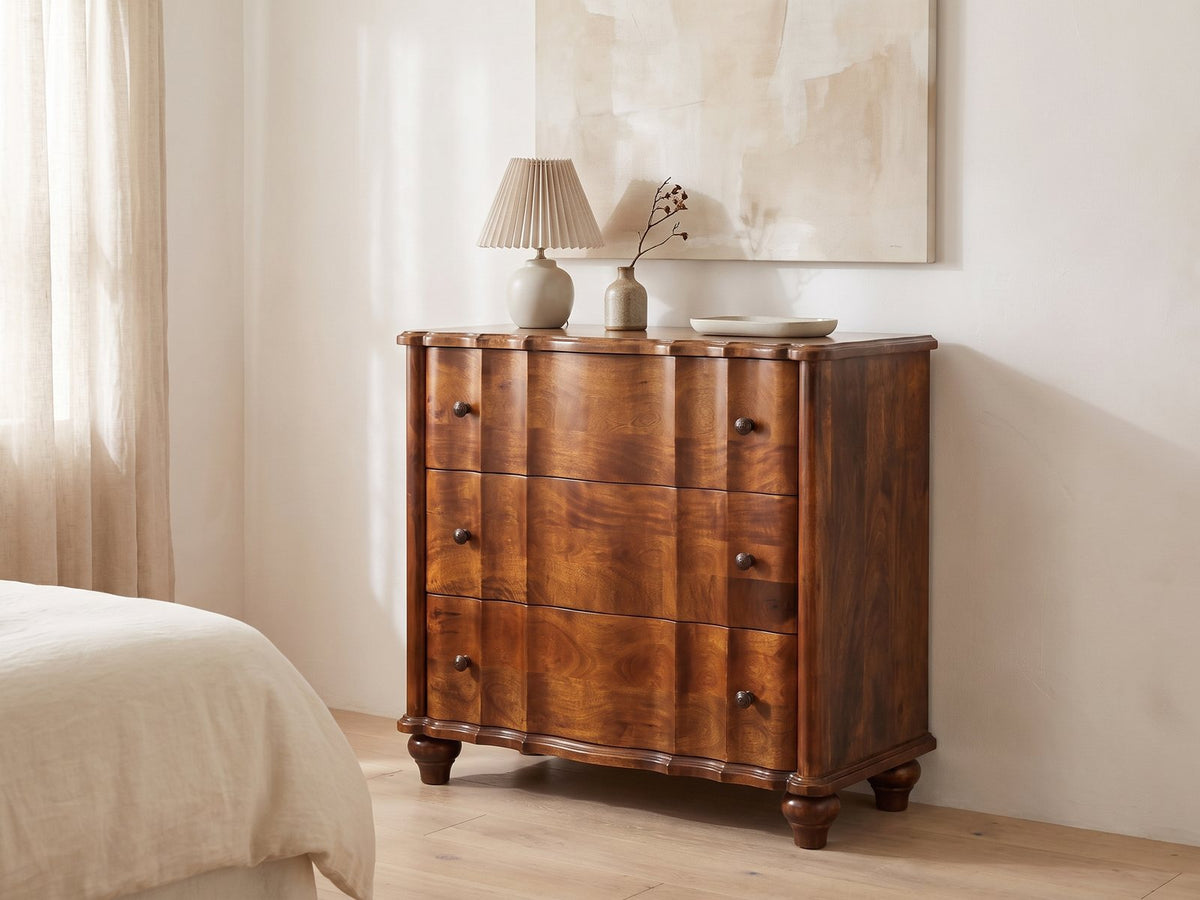 Adria 34-Inch Chestnut Solid Mango 3-Drawer Chest against a plaster wall under an abstract canvas in a bright bedroom