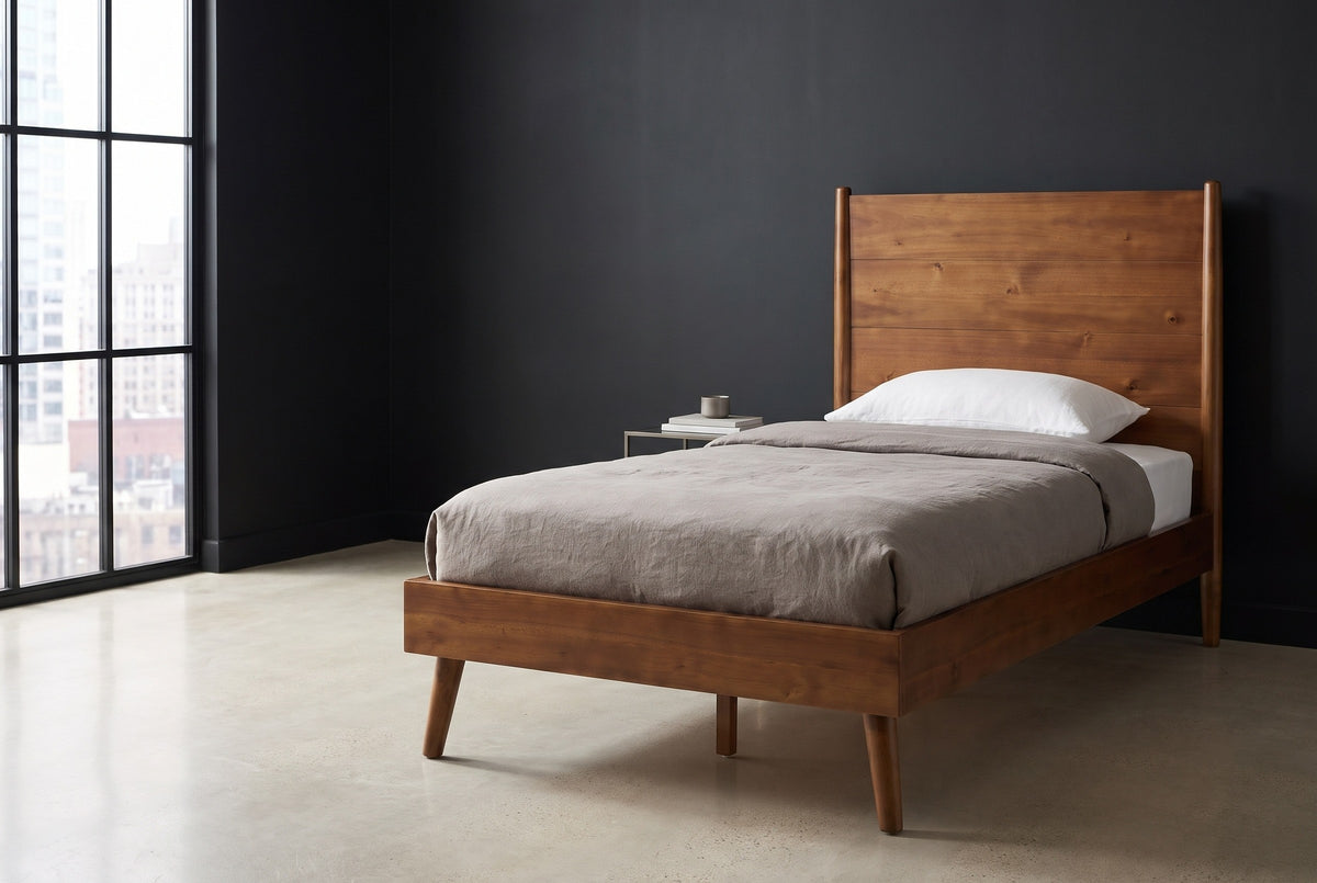 Agnone acacia platform bed with a tall board headboard against a charcoal wall in a Chicago loft, a black steel factory window at the left