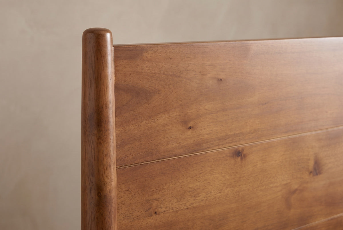 Close-up of the Agnone headboard: a slim round acacia post with a rounded top beside the horizontal boards