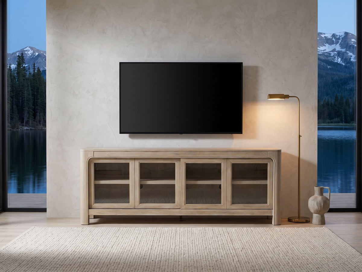 Albenga 71-Inch Weathered Mango Veneer Sliding Glass Door Media Console under a wall-mounted screen in a mountain lake house at dusk