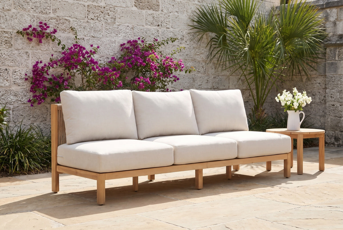 The Alcamo armless acacia sofa in a St. Augustine courtyard in front of a coquina stone wall with bougainvillea and a palm (side table not included)