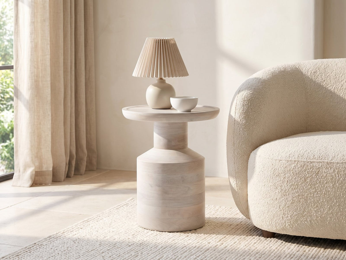 Aliano Whitewashed Mango Tray-Top Side Table with a lamp and a ceramic bowl beside a cream boucle armchair in a bright plaster room