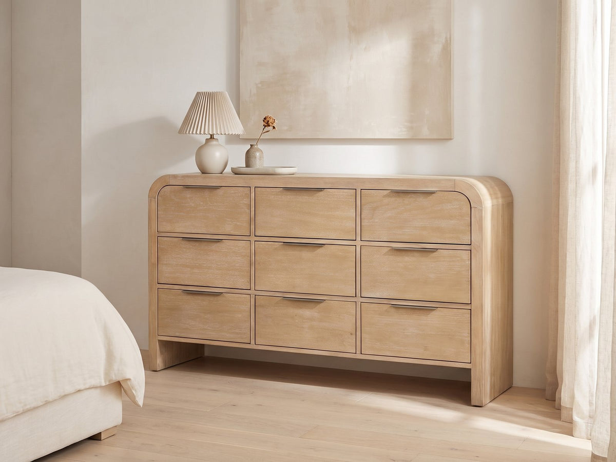 Aquileia 63-Inch Natural Mango 9-Drawer Dresser against a plaster wall under an abstract canvas in a bright bedroom