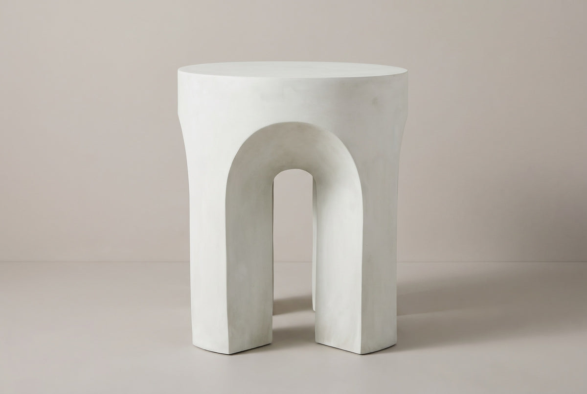 The Aragona side table seen straight on: one round-headed arch between two legs, antique white concrete