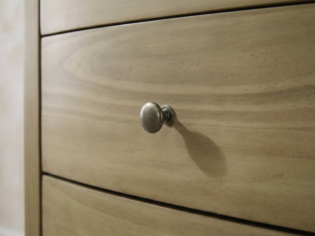Close-up of the Arqua 61-Inch Natural Pine 8-Drawer Dresser: a round antique-nickel knob on a bowed pine drawer front