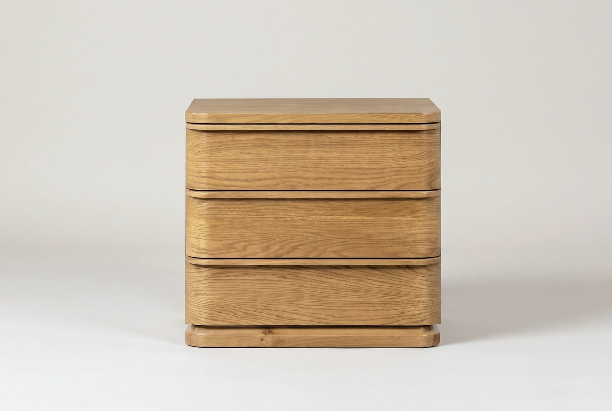 The Arzachena nightstand in natural oak, front view on a light studio backdrop