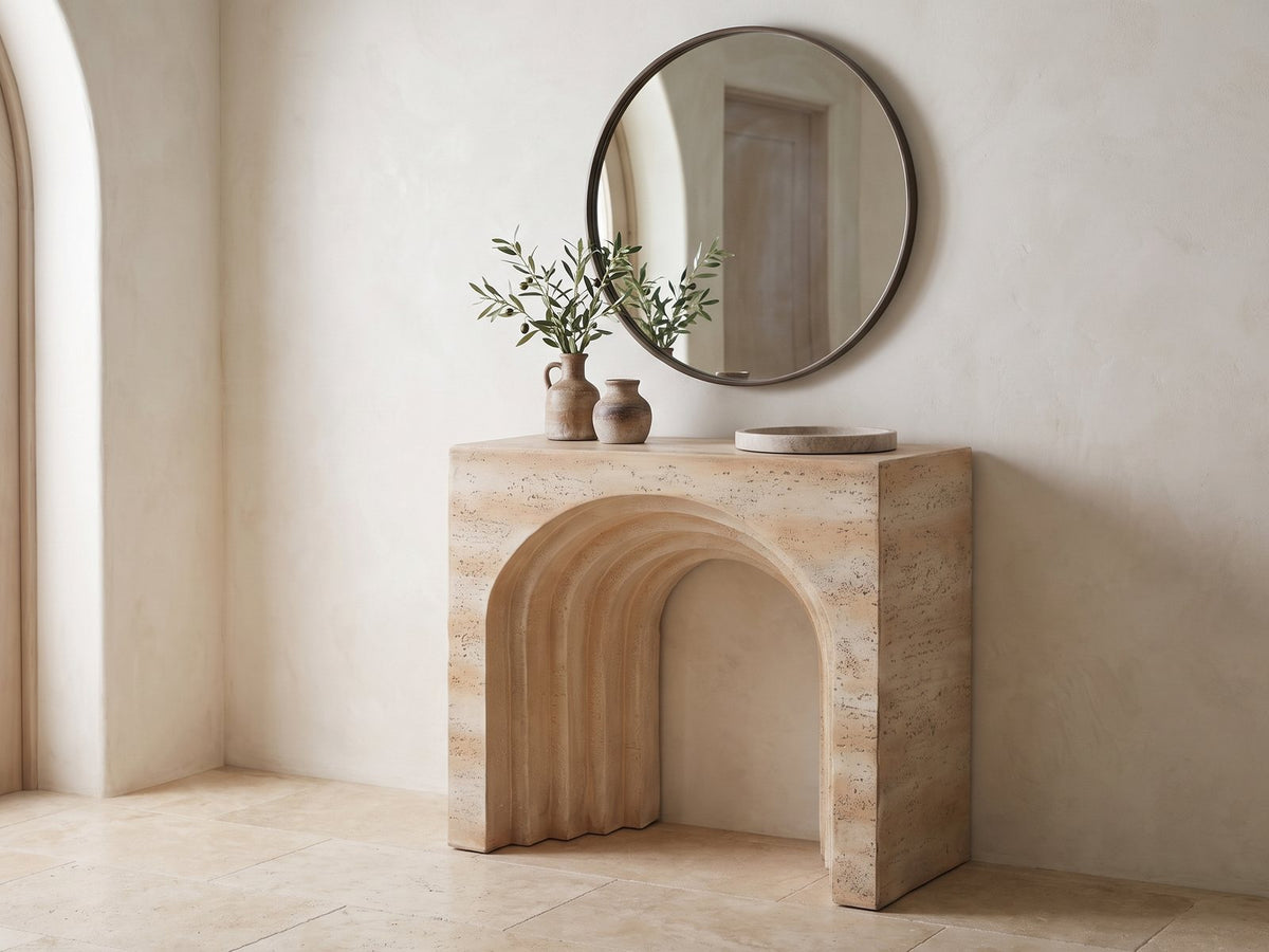 Asiago Faux Travertine Arched Console Table under a round mirror in a travertine entryway