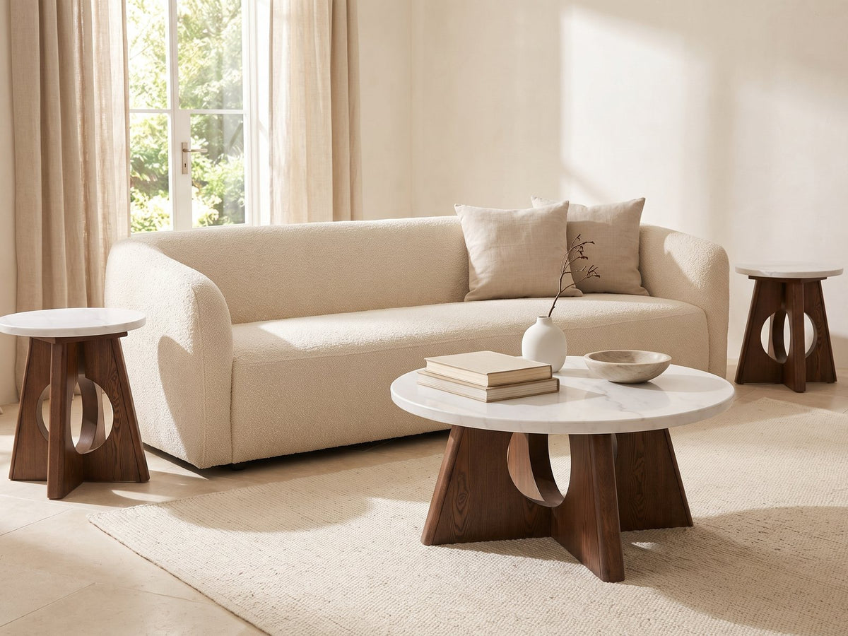 Asti 40-Inch Round White Marble Coffee and End Table Set, 3 Pieces styled with books, a vase and a stone bowl in front of a cream sofa in a bright plaster room