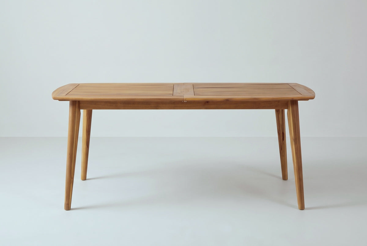 The Augusta dining table closed, seen from the long side: the thin slatted top, the apron and four tapered legs angling out toward the ends