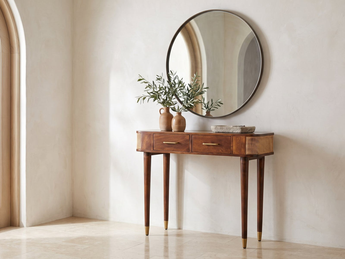Avetrana Mango Wood and Cane Console Table under a round mirror in a travertine entryway