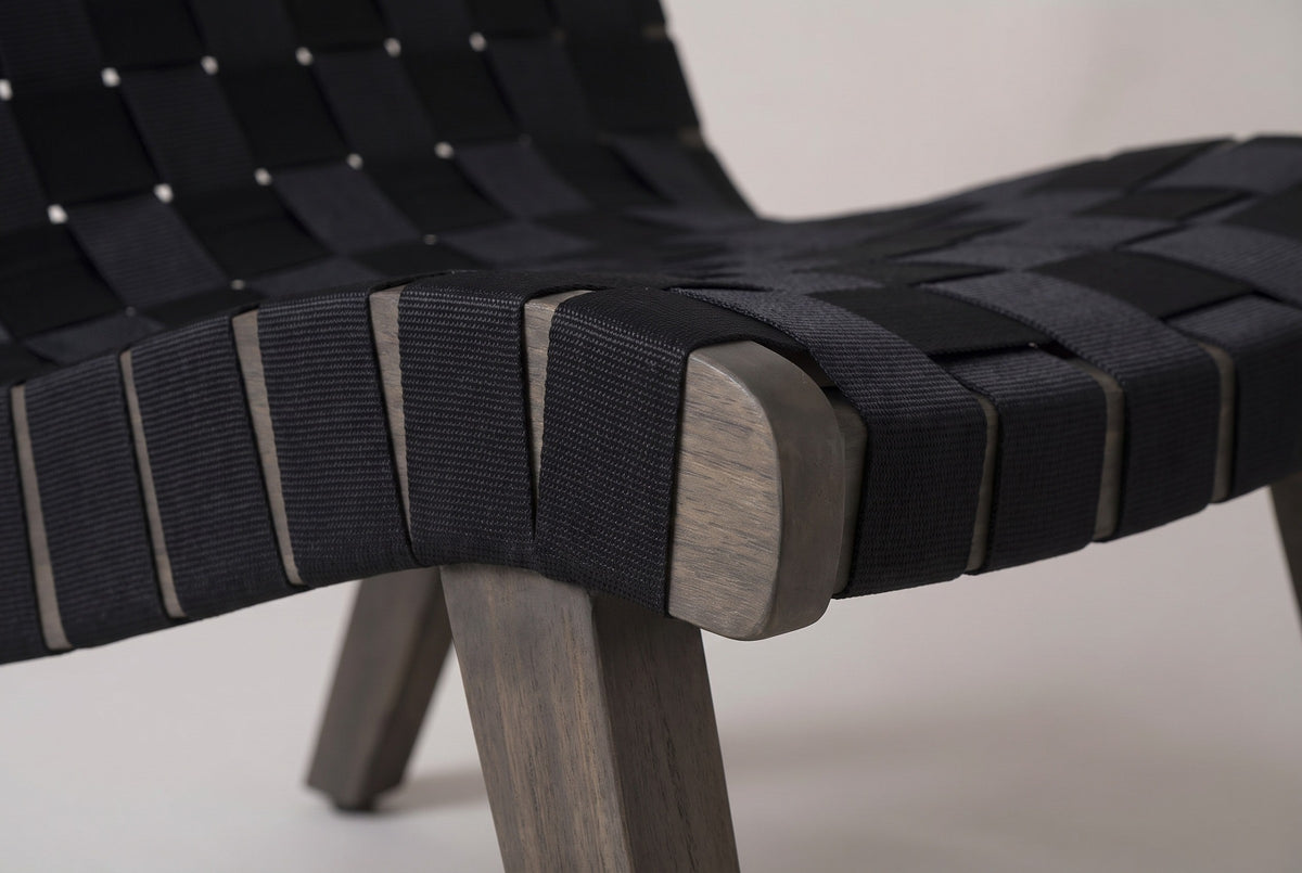 Close-up of a Bagheria seat corner: black rope straps wrapped round the grey-brown acacia side rail above a square leg
