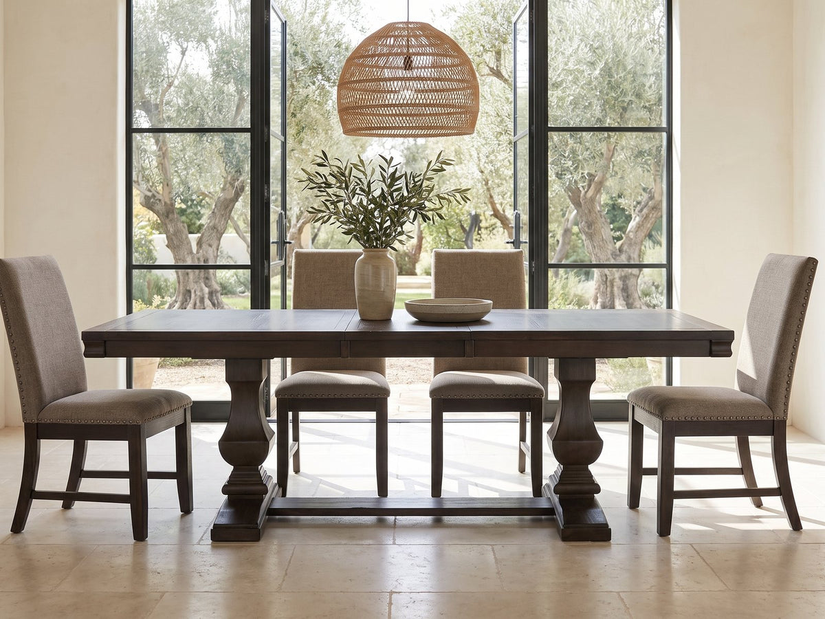 Bagnara 76.5 to 94.5-Inch Rustic Oak Double Pedestal Dining Set with 4 Chairs in a sunlit villa dining area with olive trees outside