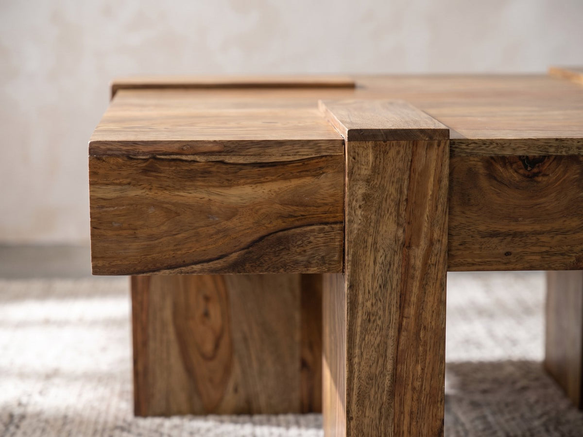 Close-up of the Barga Solid Sheesham Coffee Table: a sheesham slab leg rising flush through the thick plank edge