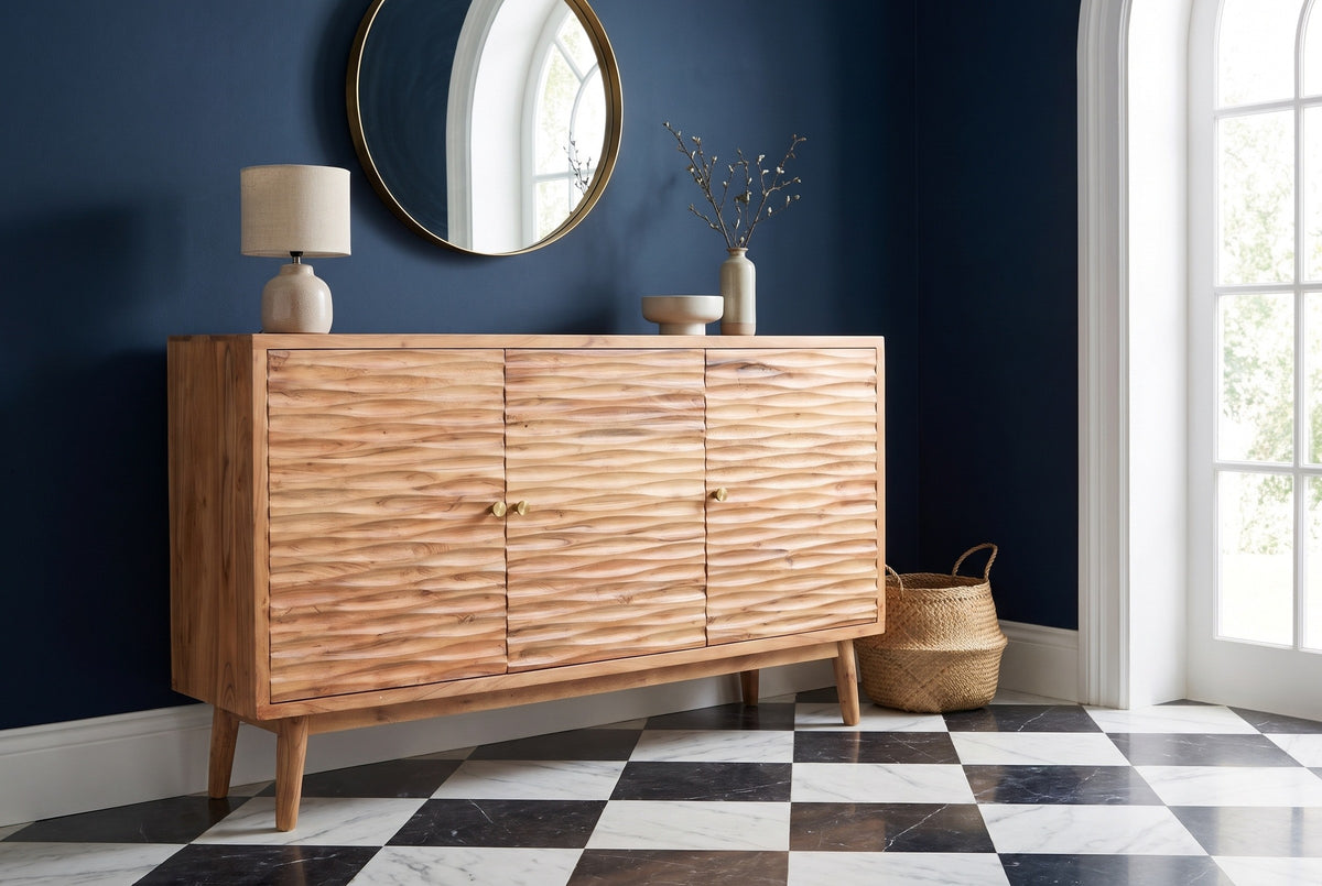 Barile carved sideboard under a round brass mirror against a deep navy wall in a Savannah entry hall with a black-and-white marble floor