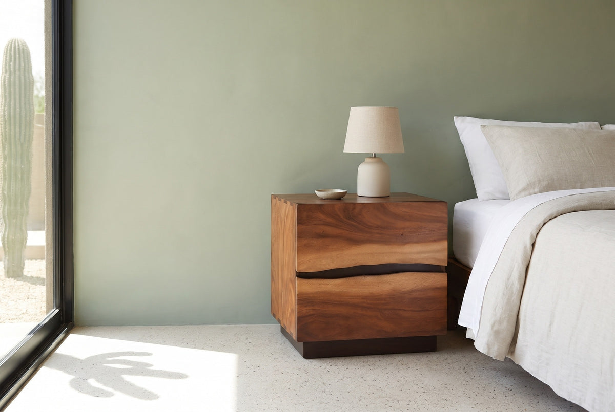 Barumini suar two-drawer nightstand with a ceramic lamp beside a bed in a Scottsdale bedroom with a sage-green wall and a tall glass window