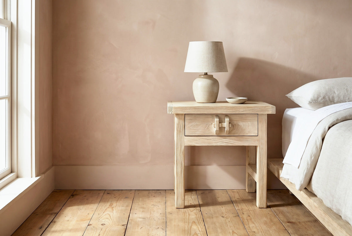 Baunei reclaimed elm nightstand with a ceramic lamp beside a low bed in a Nashville farmhouse bedroom with a dusty terracotta wall and a tall window