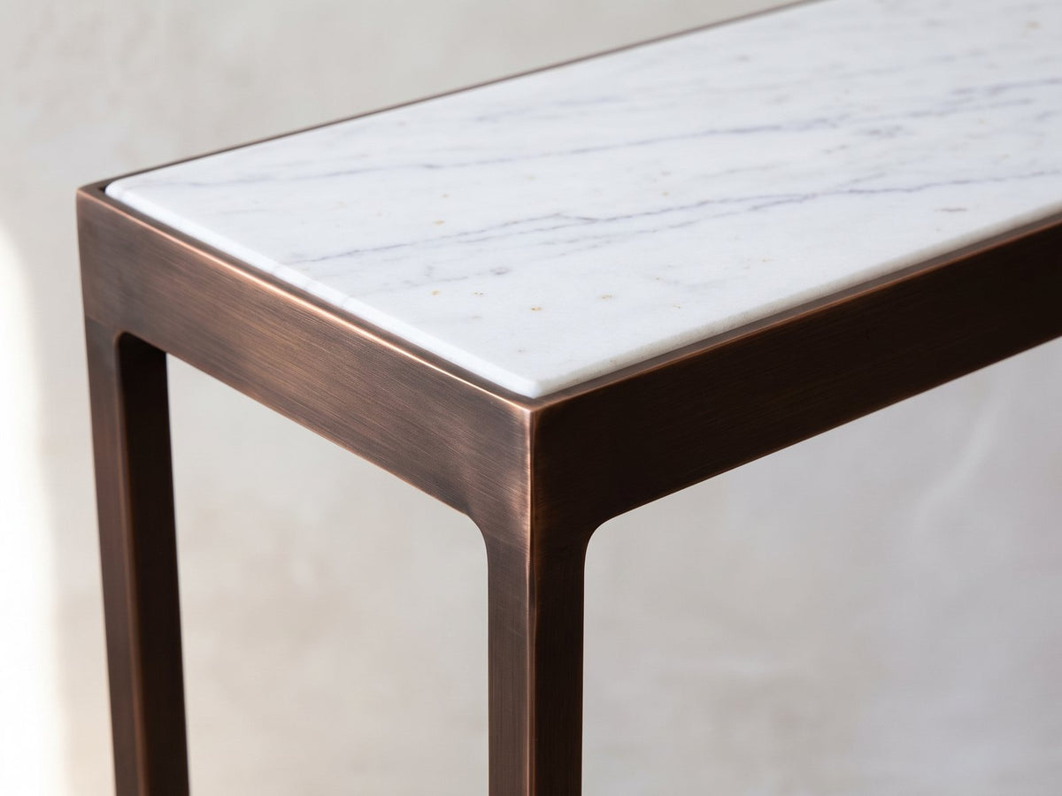 Close-up of the Bellegra White Marble Console Table: the white marble top set into the copper-finish iron frame at one corner