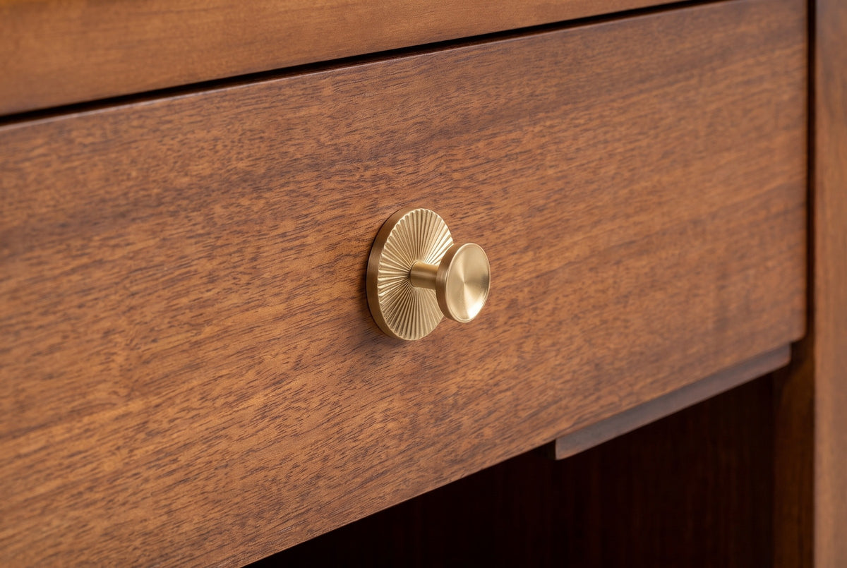 The Berchidda drawer front in walnut veneer with its round brass-tone knob on a ribbed sunburst rosette