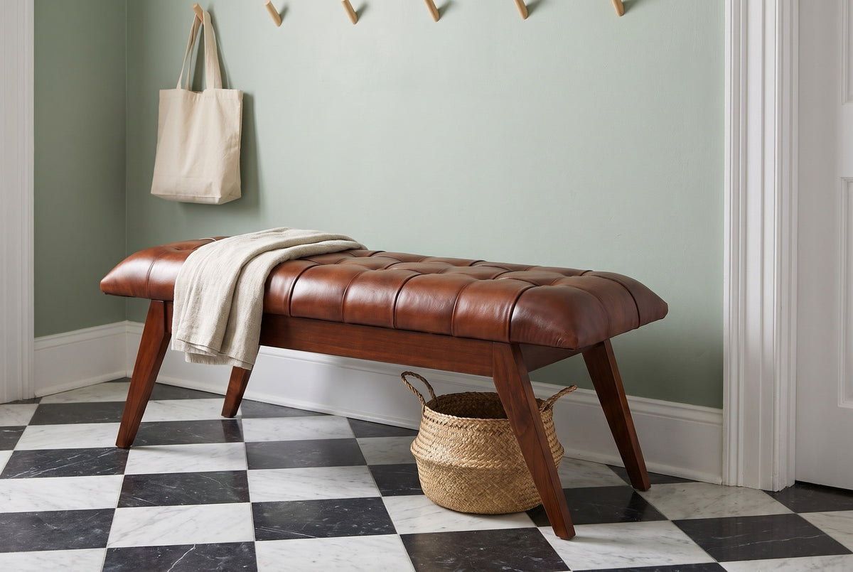 Bevagna cognac leather bench in a Charleston entry hall with a sage-green plaster wall, a black-and-white checkerboard marble floor, a folded linen throw and a seagrass basket