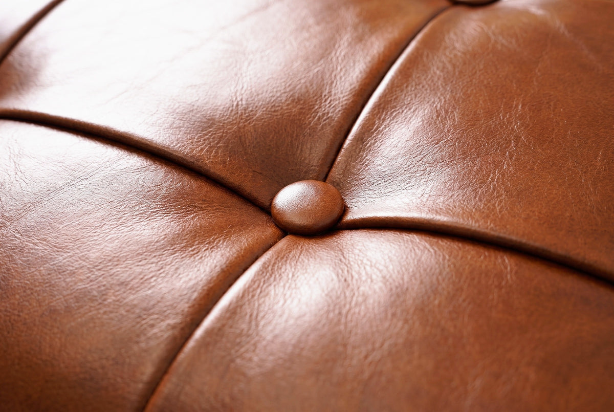 Close-up of the genuine leather on the Bevagna bench: warm cognac leather with fine natural grain, a raised seam and one leather-covered button