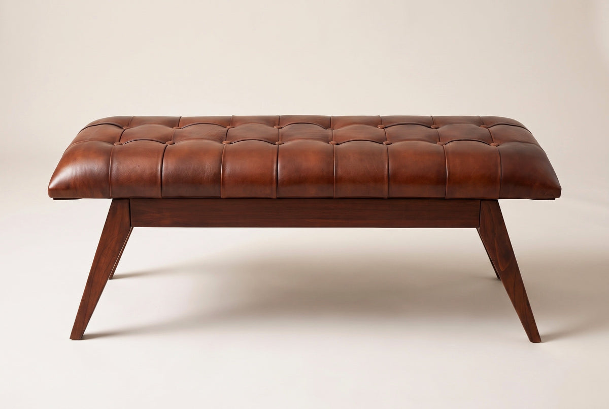 The Bevagna bench, front view on a light studio backdrop: eight seams across the leather cushion, a plain wood apron and four angled legs