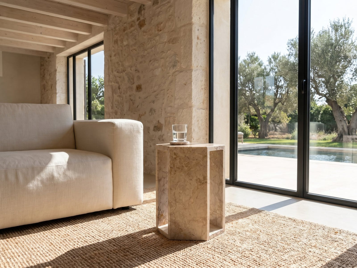 Bojano Rosa Marble Hexagon Side Table beside a linen sofa in a poolside villa