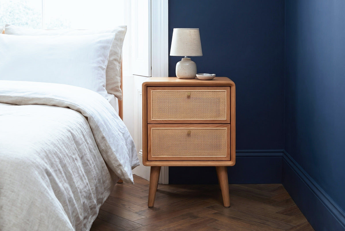 Bono oak and cane nightstand against a deep navy wall in a Brooklyn brownstone bedroom with a herringbone parquet floor