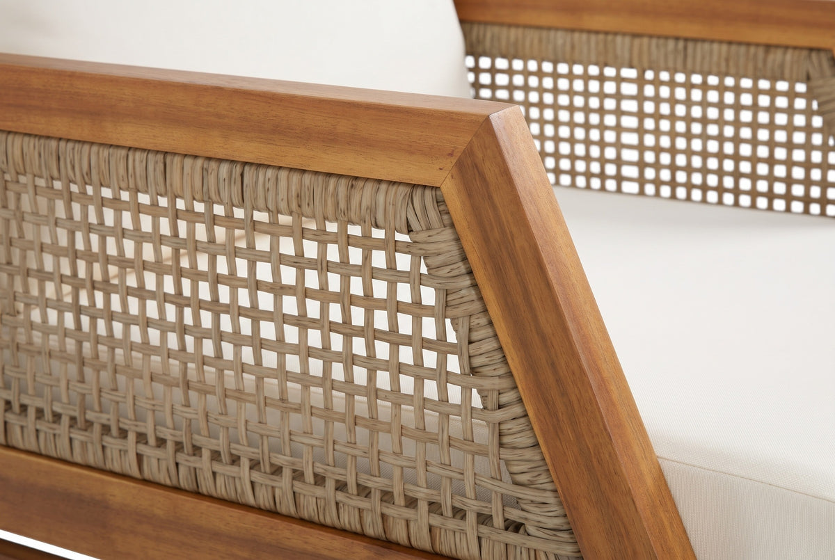 Close-up of a Buccheri arm: the acacia arm rail meeting the slanted front member, the open flat-wicker grid inside and the ivory cushion beside it