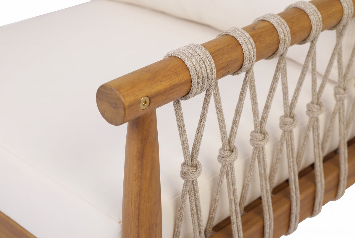 Close-up of a Burgio arm: the round teak-finish acacia rail and tapered front post, beige rope loops and knots, and the cream cushion behind