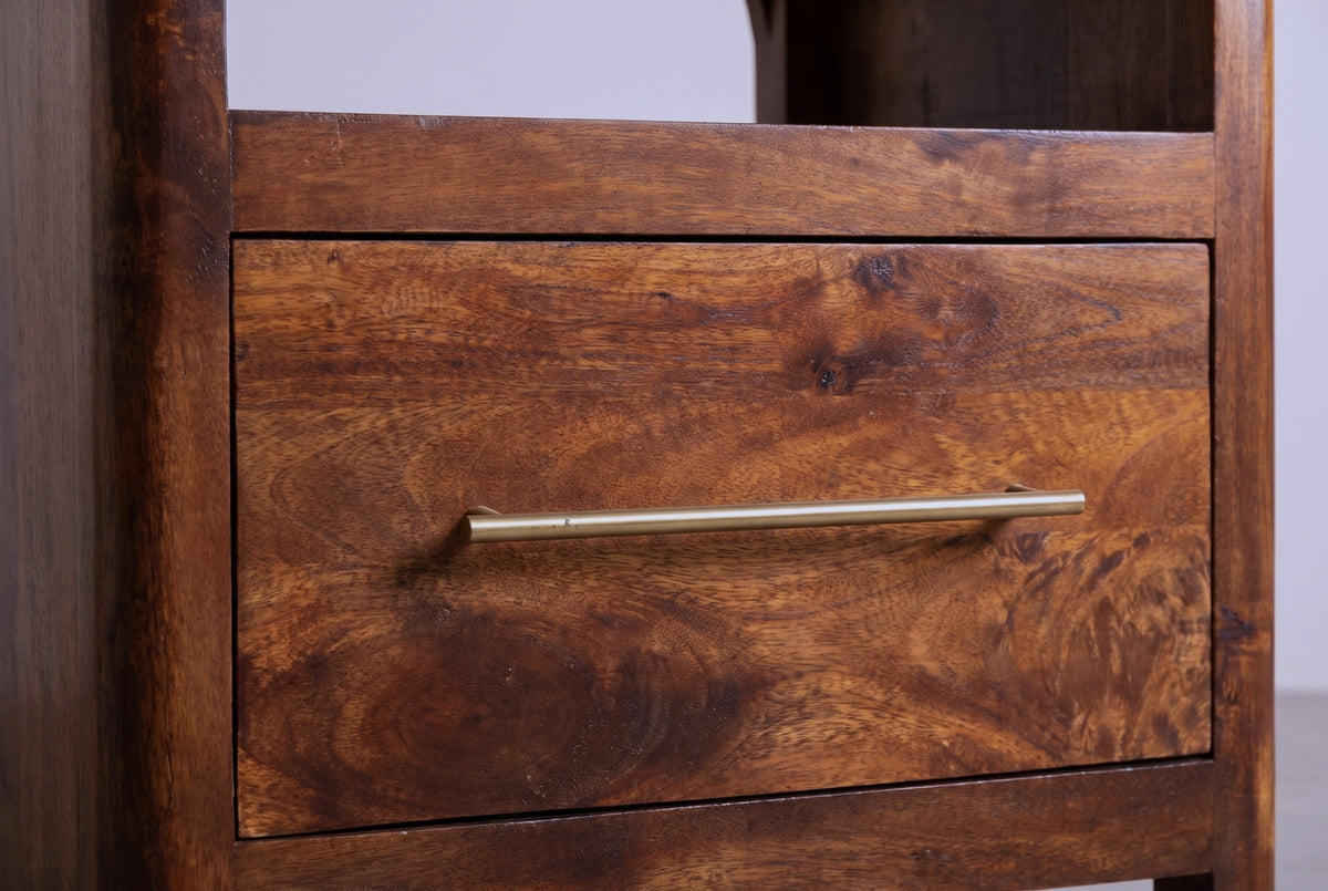 The drawer of the Cabras nightstand: a flat mango drawer front with a long slim brass bar pull, and the curve of the arched cubby above