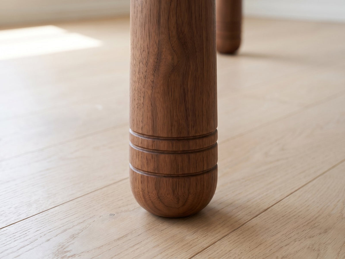 Close-up of the Caccuri 63-Inch Sintered Stone Walnut-Finish Dining Set with 4 Chairs: a cylindrical walnut-finish leg with three incised rings above its rounded foot