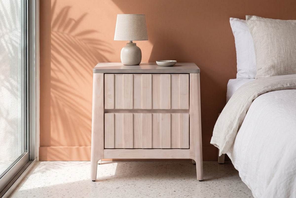 Calangianus whitewash nightstand with a ceramic lamp against a terracotta plaster wall in a Palm Springs bedroom with a terrazzo floor and a palm shadow on the wall