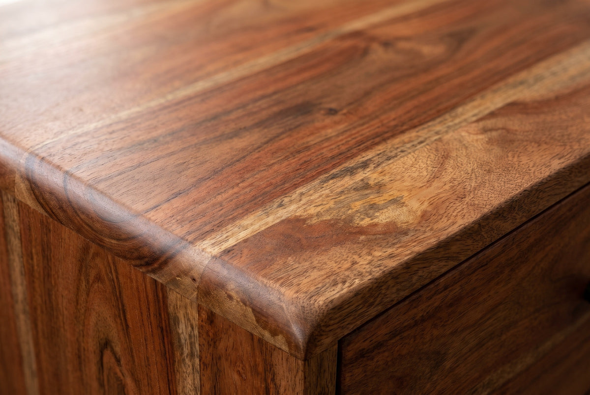 Close-up of the chestnut mango wood on the Calasetta nightstand: reddish brown grain with golden streaks running to a rounded edge