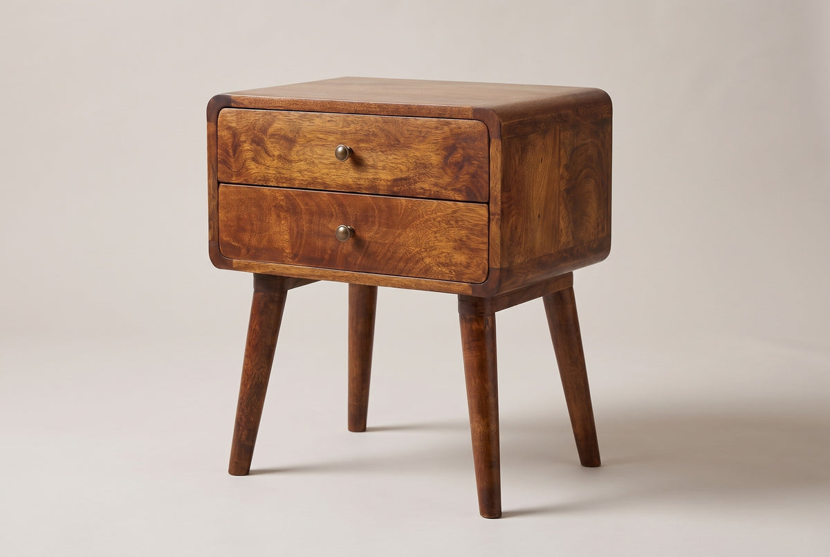 The Calasetta two-drawer nightstand in chestnut mango with brass knobs, rounded corners and four splayed round legs, three-quarter view on a light studio backdrop