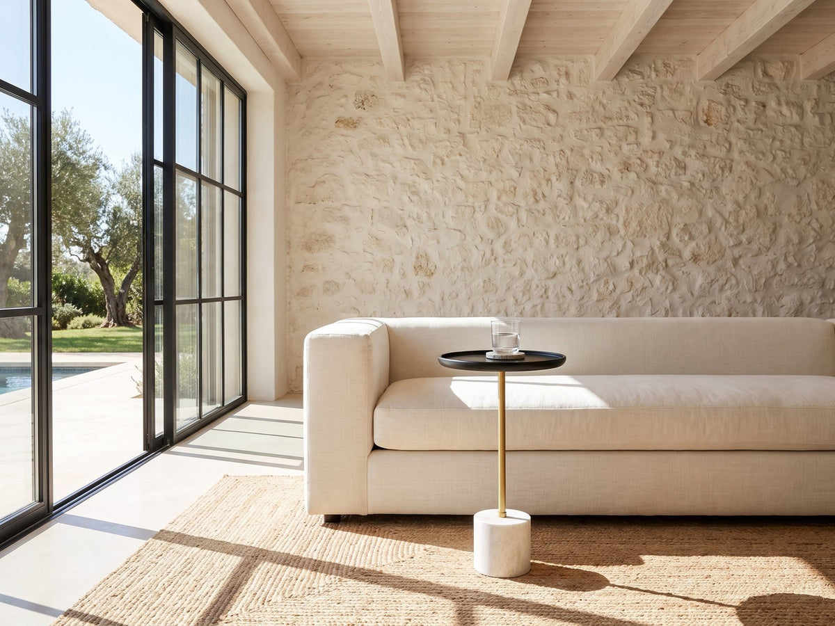 Calimera Black Mango and Marble Pedestal Side Table beside a linen sofa in a poolside villa
