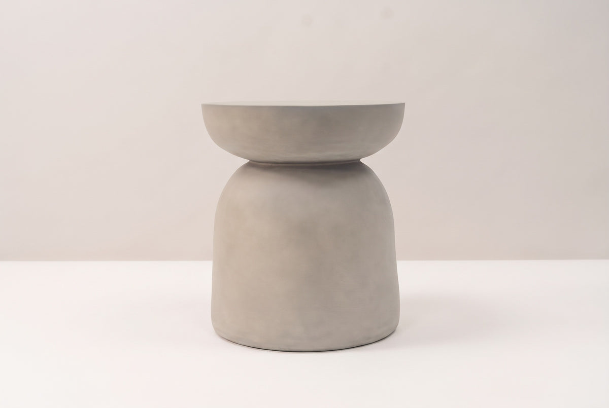 The Cammarata side table seen straight from the side: a light grey dish top, a slim neck and a bell base with nearly straight sides