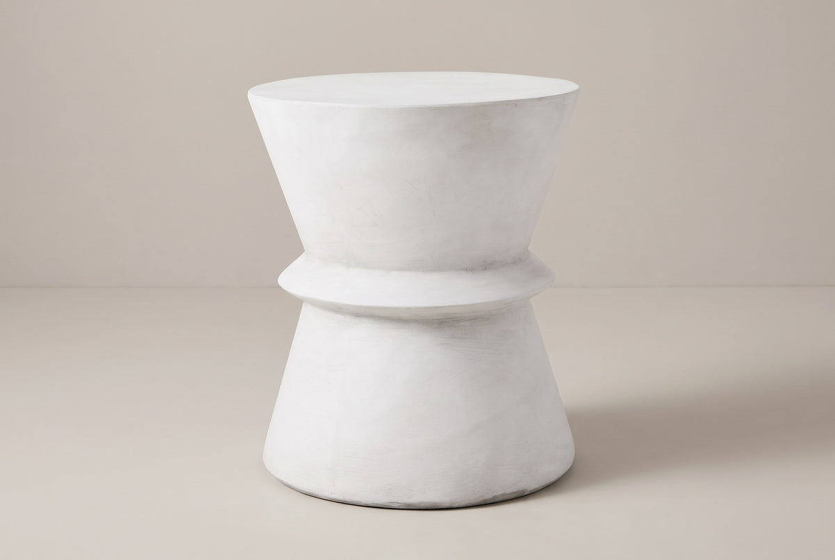 The Capizzi antique white concrete hourglass side table, three-quarter view on a light studio backdrop