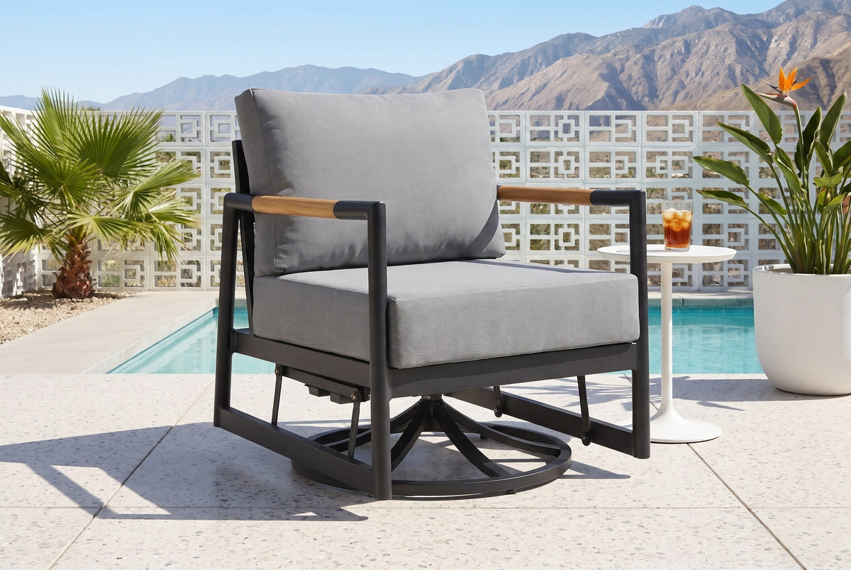 The Carini swivel glider lounge chair on a terrazzo pool patio in Palm Springs, a white breeze-block wall, a fan palm and the mountains behind (side table and drink not included)