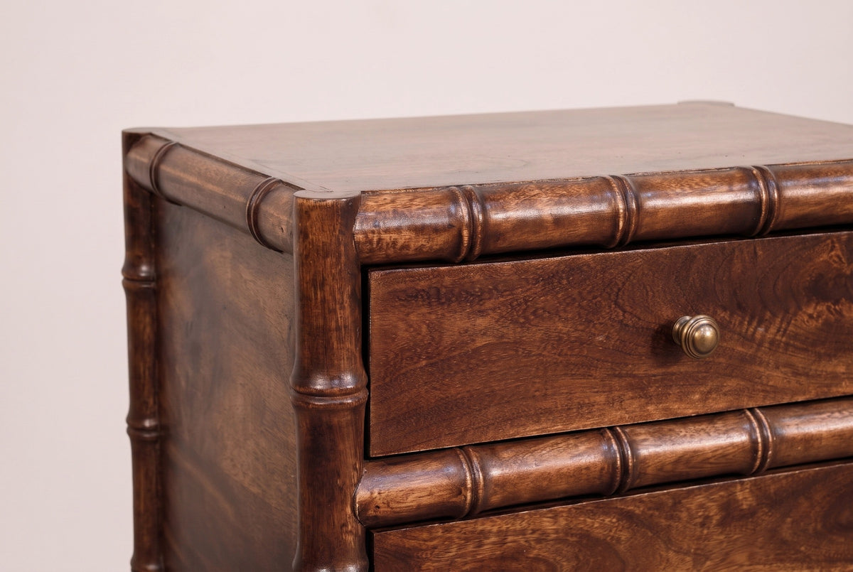 The top corner of the Carloforte nightstand: the thin top, the turned faux-bamboo rail and corner post with raised rings, the top drawer with its brass knob and the middle rail