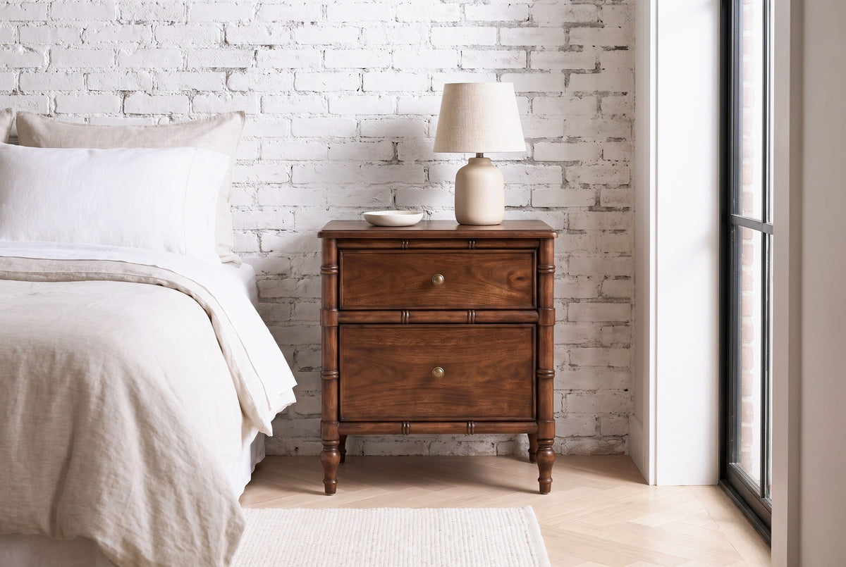 Carloforte faux-bamboo mango nightstand against a whitewashed brick wall in a Brooklyn brownstone bedroom with a herringbone oak floor