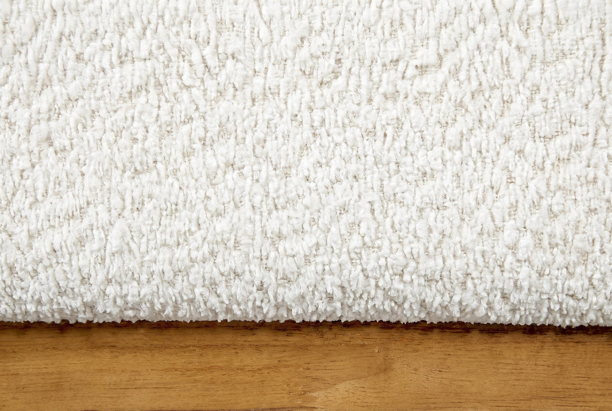 Close-up of the white boucle on the Casoli bed above the natural rubberwood plinth
