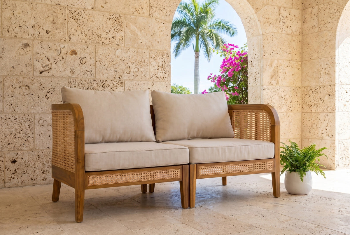 Castelbuono acacia and cane arm chairs joined in a Coral Gables loggia with coral stone walls, travertine floor and an arched view of a royal palm (planter not included)