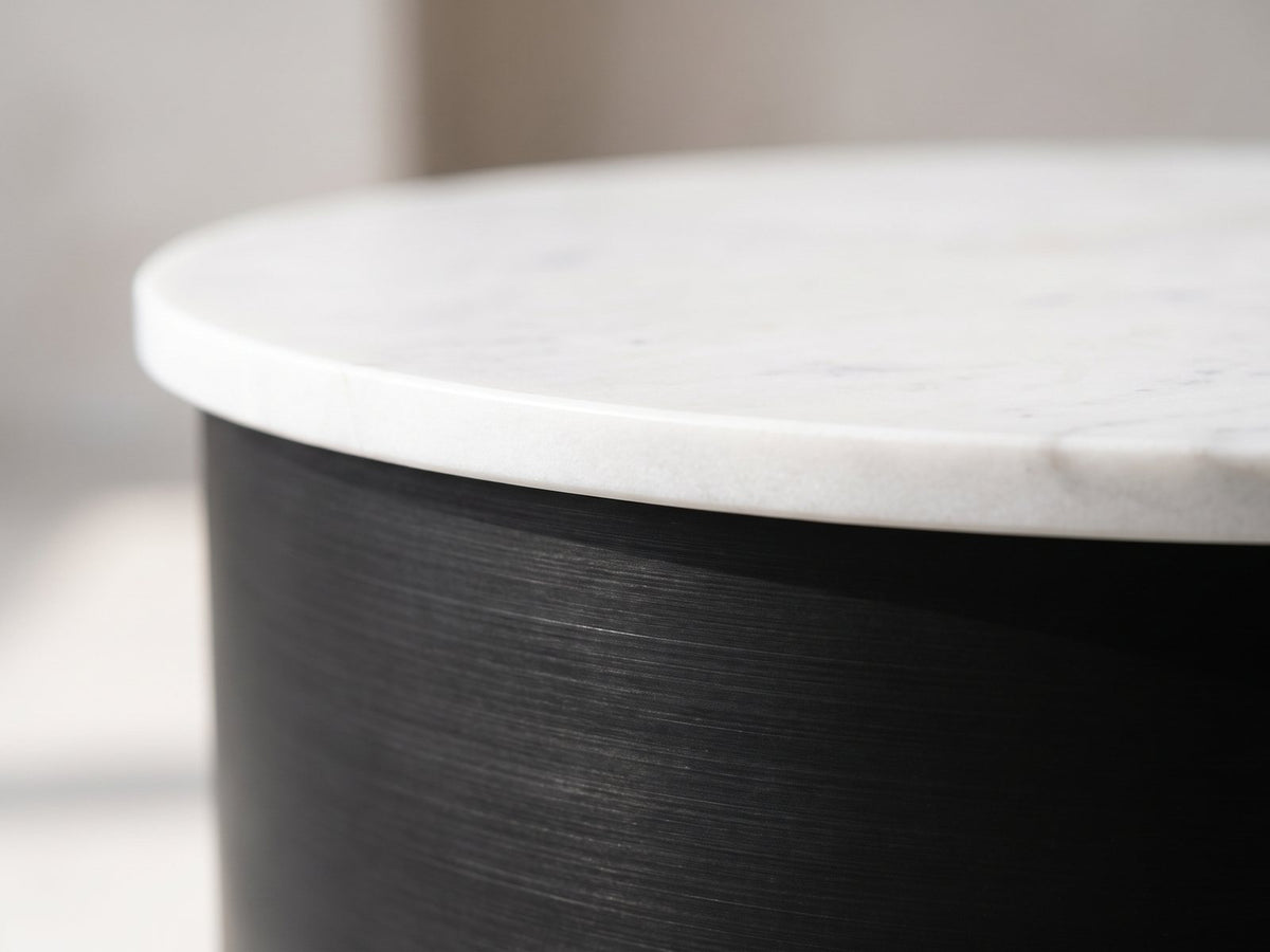 Close-up of the Ceglie White Marble Hourglass Side Table: the white marble top resting on the black iron drum