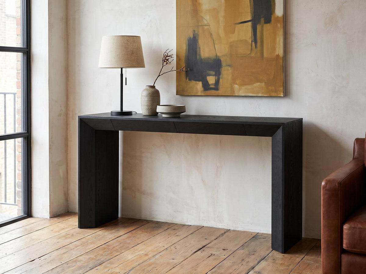 Cellamare Black Ash Veneer Waterfall Console Table against a plaster wall in an industrial loft