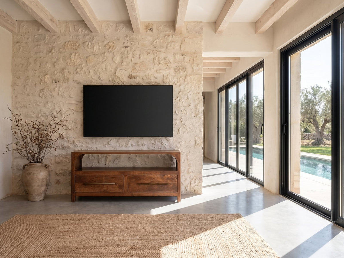 Cherasco Arch Mango Media Console under a wall-mounted screen on a pale stone wall in a poolside villa