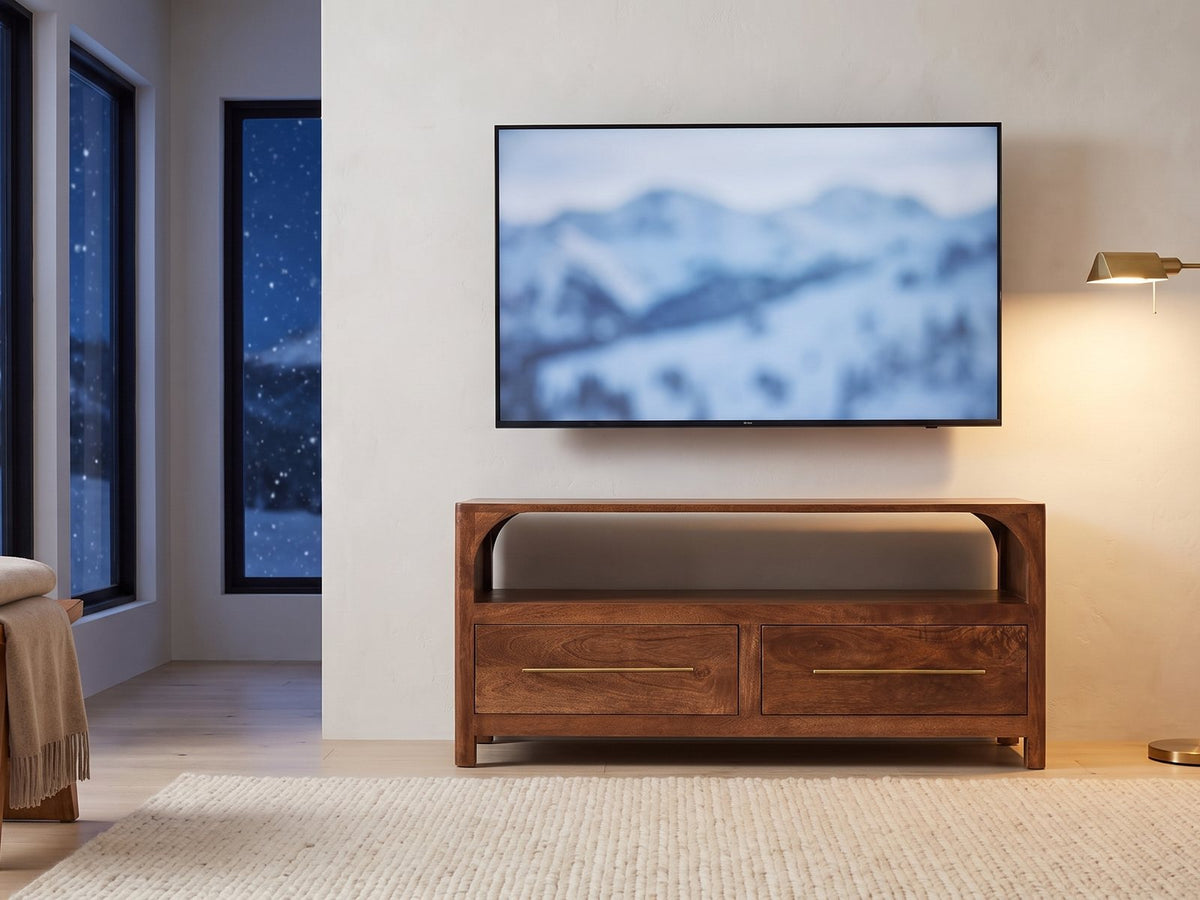Cherasco Arch Mango Media Console under a screen showing a snowy landscape on a winter evening