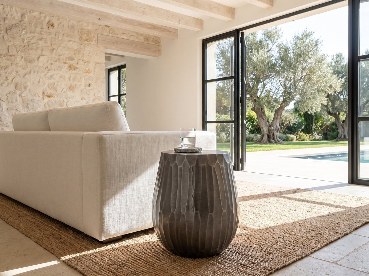 Chianciano Cast Aluminum Faceted Drum Side Table beside a linen sofa in a poolside villa