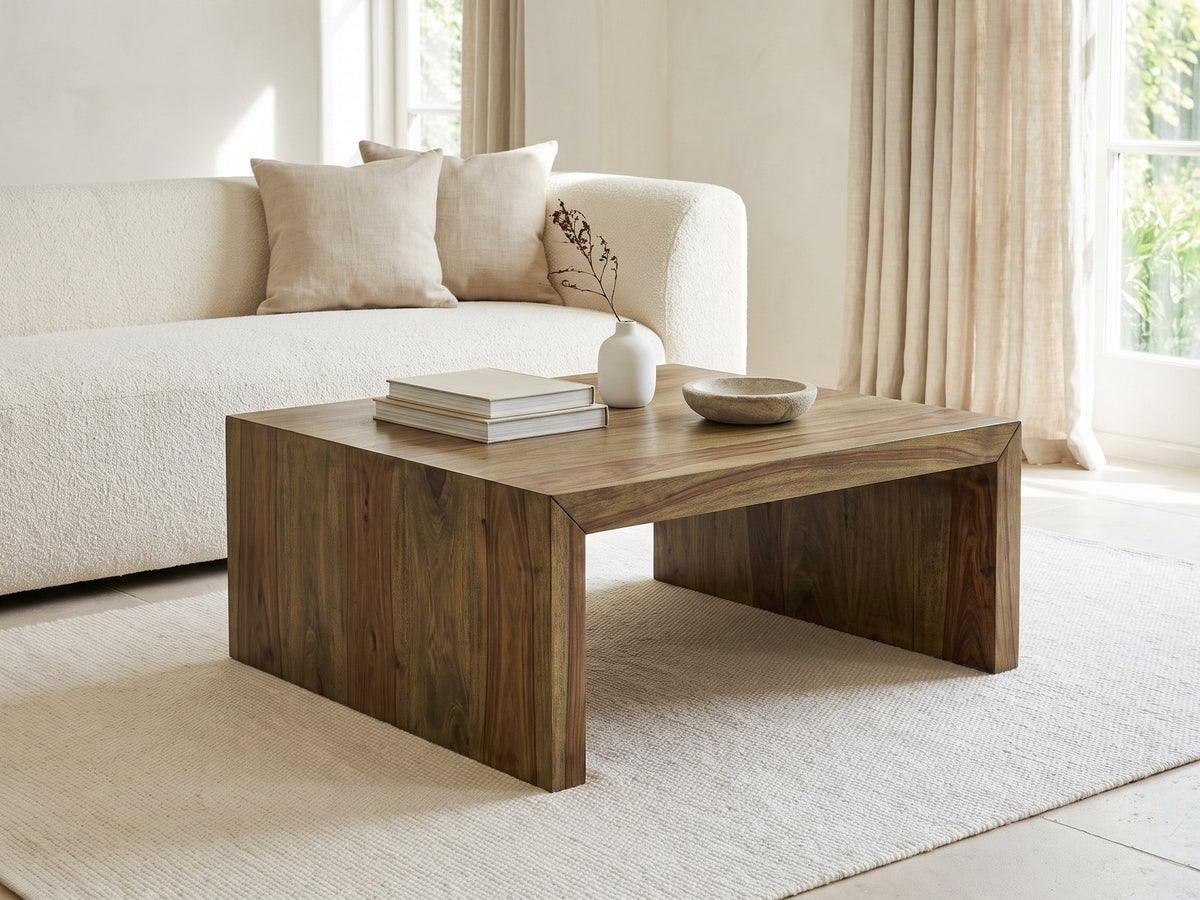 Chieri 34-Inch Square Solid Sheesham Waterfall Coffee Table styled with books, a vase and a stone bowl in front of a cream sofa in a bright plaster room