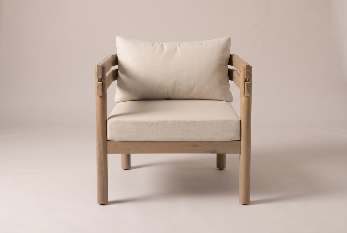 One Cinisi chair seen from the front: the beige back cushion and seat cushion between the two acacia arms on round legs